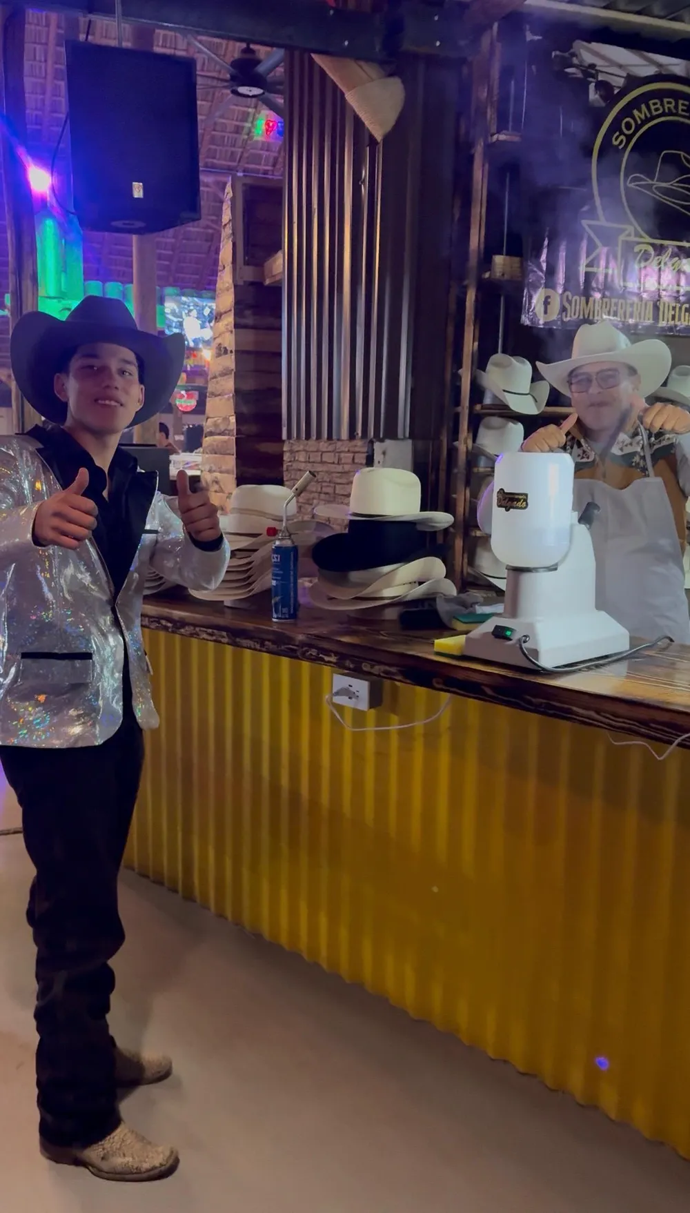 Cliente satisfecho con su sombrero frente al mostrador del taller